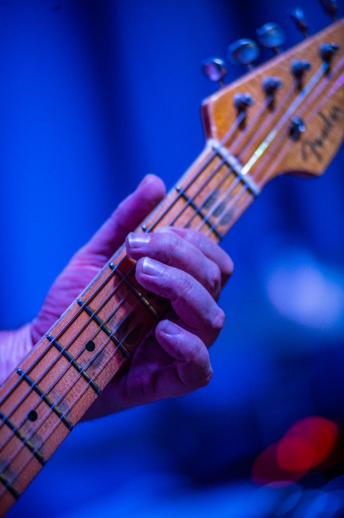 Intense close-up of a musician's hand playing an electric guitar on stage.
